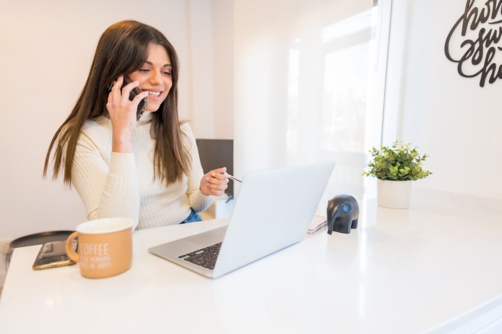 Portrait of businesswoman working with a computer smiling at the phone, business, home office